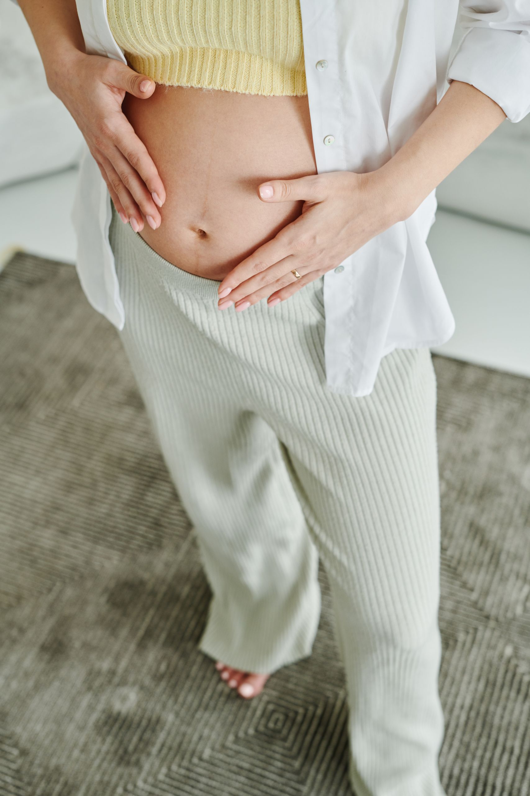 A serene close-up of a woman gently holding her pregnant belly, expressing motherhood.
